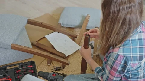 Woman assembling chair by hand using manual tools at home Stock Footage 313398938