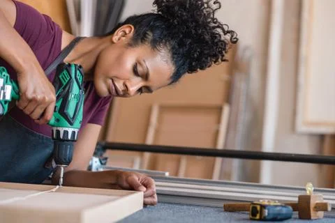 Woman assembling a frame using a drill in her workshop Stock Photos