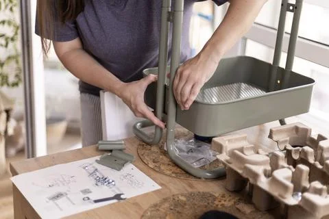 Woman assembling metal shelf unit with instructions and tools on Stock Photos