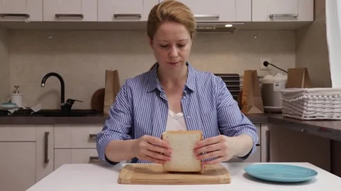 Woman assembling a sandwich, combines bread with jam and peanut butter Stock Footage 250385028