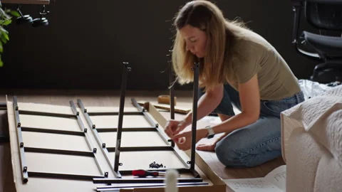 Woman assembling shelving frame on floor in home office Stock Footage 343319318