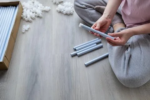 Woman assembling a structure with plastic tubes and connectors on a wooden .. Stock Photos