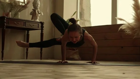 Woman athlete performs complex element of yoga at home Stock Footage 170747319