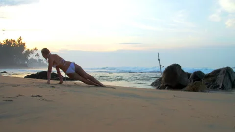 Woman athlete performs side plank pose against ocean in mist 스톡 동영상 274569806
