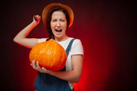 Woman attacks with a sharp knife while holding a pumpkin for Halloween Stock-Fotos