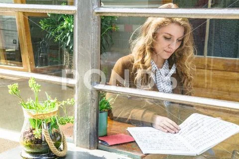 Woman attentively reading music score in cafe Stock Photos