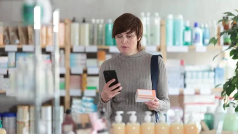 Woman in autumn clothes scans code on package of pills to check the expiration Stock Footage 313457266