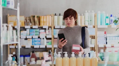 Woman in autumn clothes scans code on package of pills to check the expiration Stock Footage 341376879