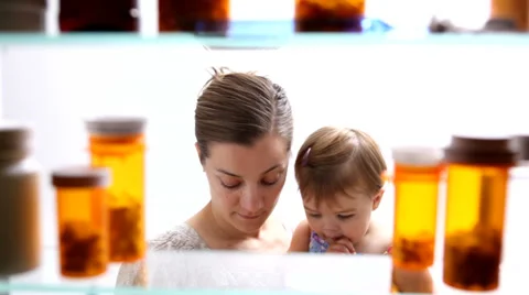 Woman with baby gets medicine out of cabinet Stock Footage