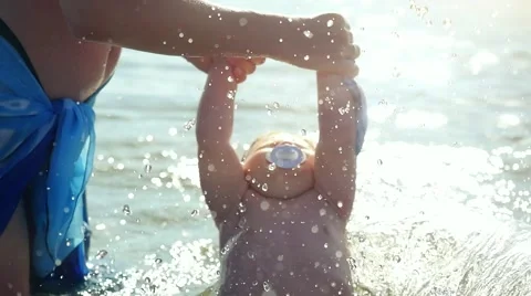 Woman with baby playing against splashes of water in the summer in slowmotion at 스톡 동영상 59088162
