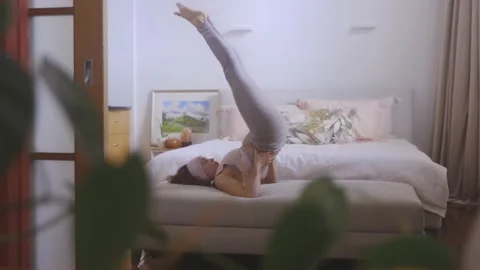 Woman in the background practicing yoga in her bedroom Stock Footage 161095415