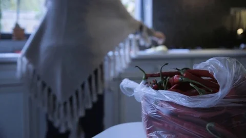 Woman in background working in kitchen with red peppers in foreground Stock Footage 72559093