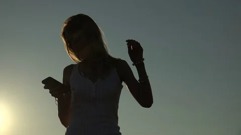 Woman backlit listen the music with smartphone and dancing Stock Footage