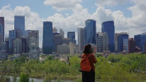 Woman with backpack and camera observing Calgary skyline and Bow River Stock-Footage 330880314