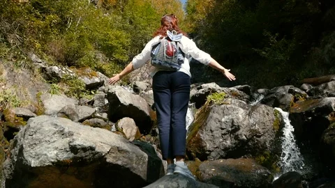 Woman with backpack exploring in summer forest, looking at waterfall. Stock Footage 100256088