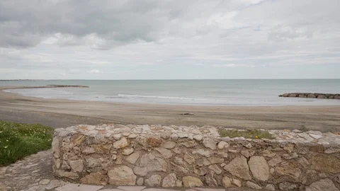 Woman with backpack goes down stone path to sea in inclement weather. Rear view 스톡 동영상 123549403