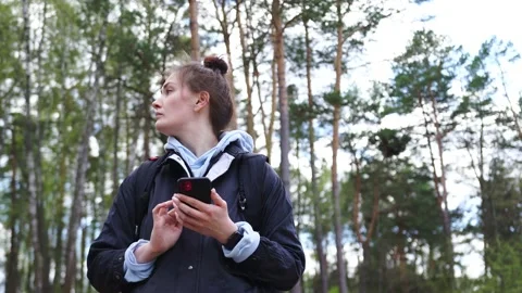 Woman with a backpack looking the route on the maps on the phone in the forest Stock Footage 153984612