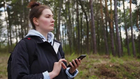 Woman with a backpack looking the route on the maps on the phone in the forest Stock Footage 153984799