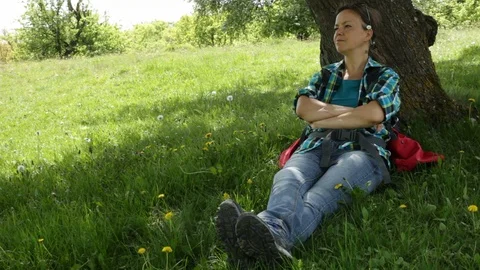 Woman with backpack sitting under the tree enjoying shade Stock Footage 89667779