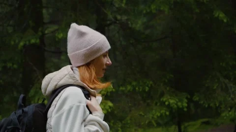 Woman with backpack thoughfully walking in the forest. 스톡 동영상 296576293