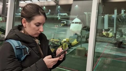 Woman with backpack using her smartphone and texting messages at the airport Video stock 337810433