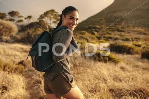 Woman with backpack walking up the country trail Stock Photos