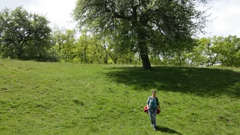 Woman with backpack walking down a meadow on a hill Stock Footage 89667742