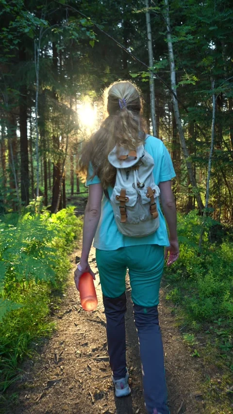 Woman with backpack walking on sunlit forest path Stock Footage 331883240
