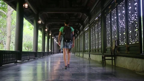 Woman with backpack walking through Southeast Asian temple, capturing culture Stock Footage 248513530