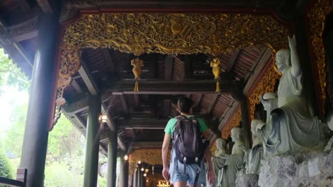 Woman with backpack walking through Southeast Asian temple, capturing culture Stock Footage 248513644