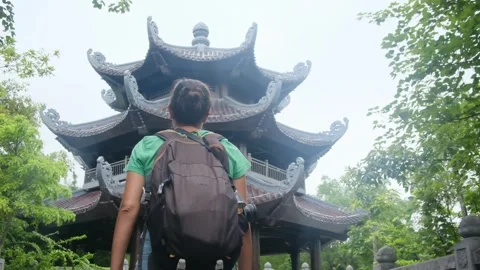 Woman with backpack walking through Southeast Asian temple, capturing culture Stock Footage 248513684