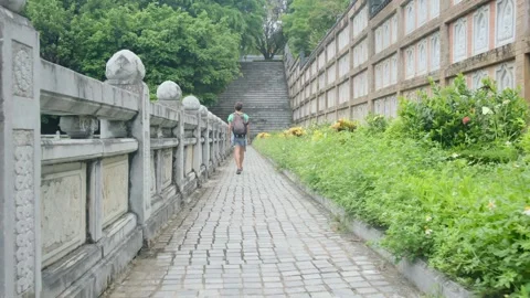 Woman with backpack walking through Southeast Asian temple Stock Footage 248513815