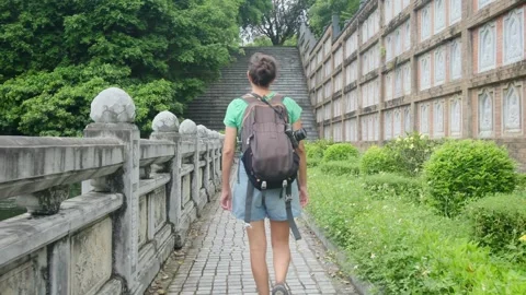 Woman with backpack walking through Southeast Asian temple Stock Footage 248513829