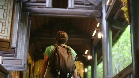 Woman with backpack walking through Southeast Asian temple Stock Footage 248513965