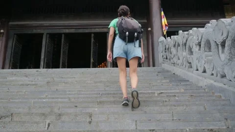 Woman with backpack walking through Southeast Asian temple Stock Footage 248514019