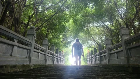 Woman with backpack walking through Southeast Asian temple, capturing culture Stock Footage 248514040