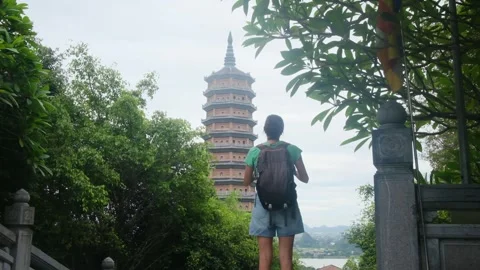 Woman with backpack walking through Southeast Asian temple, capturing culture Stock Footage 248514441