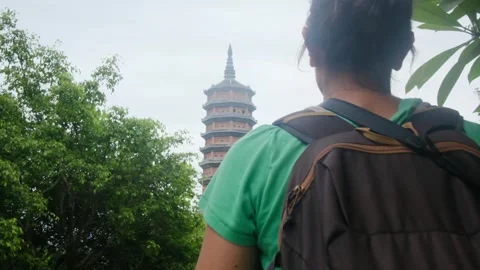 Woman with backpack walking through Southeast Asian temple Stock Footage 248514493