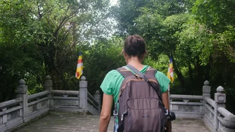Woman with backpack walking through Southeast Asian temple, capturing culture Stock Footage 248515842