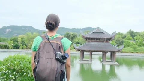 Woman with backpack walking through Southeast Asian temple Stock Footage 248515862