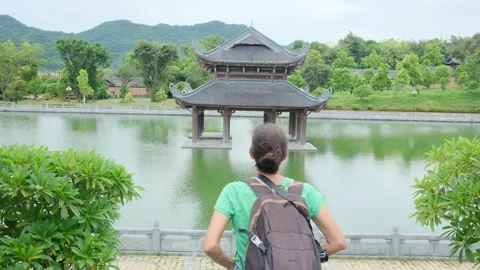 Woman with backpack walking through Southeast Asian temple Stock Footage 248515925