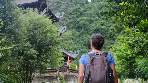 Woman with backpack walking through Southeast Asian temple Stock Footage 248516643