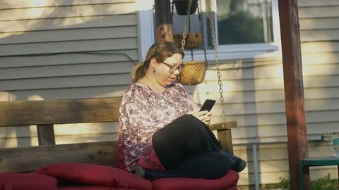 Woman on Backyard Swing  using cell phone Stock Footage 179224069