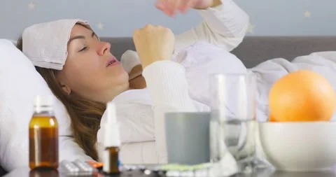 Woman with bad cold, flu or coronavirus fever lying in bed near the medicine  Stock Footage 201100686