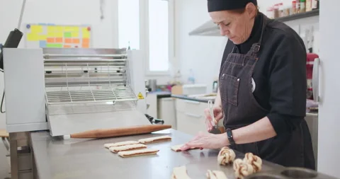 Woman baker preparing raw dough for pastry on baking manufacture Stock Footage 237908036