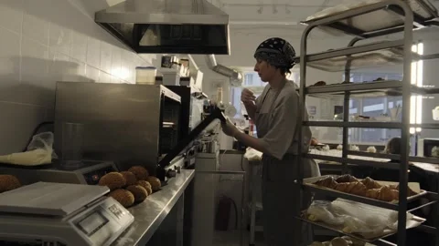 A woman baker puts a baking sheet with croissants in the oven  Stock Footage 267016271