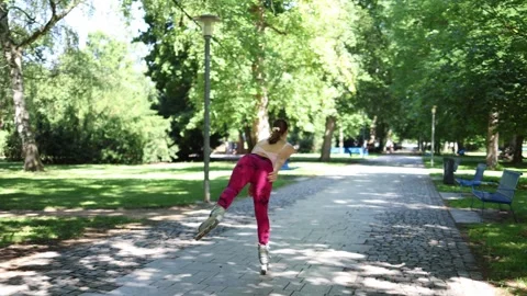 Woman balances on one inline skate while rollerblading through a sunny park Video stock 342267708