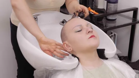 A woman in a barbershop is washing her head after shaving Stock Footage