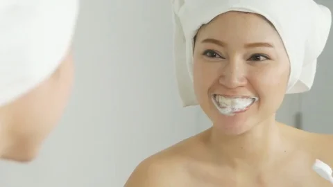 Woman in bath towel brushing teeth with mirror in the bathroom Stock Footage
