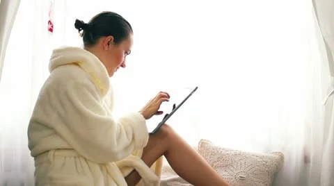 Woman in bathrobe with tablet computer by the window HD Stock Footage 10608374